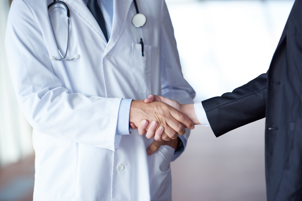 doctor handshake with a patient at doctors bright modern office in hospital doctor handshake with a patient at doctors bright modern office in hospital